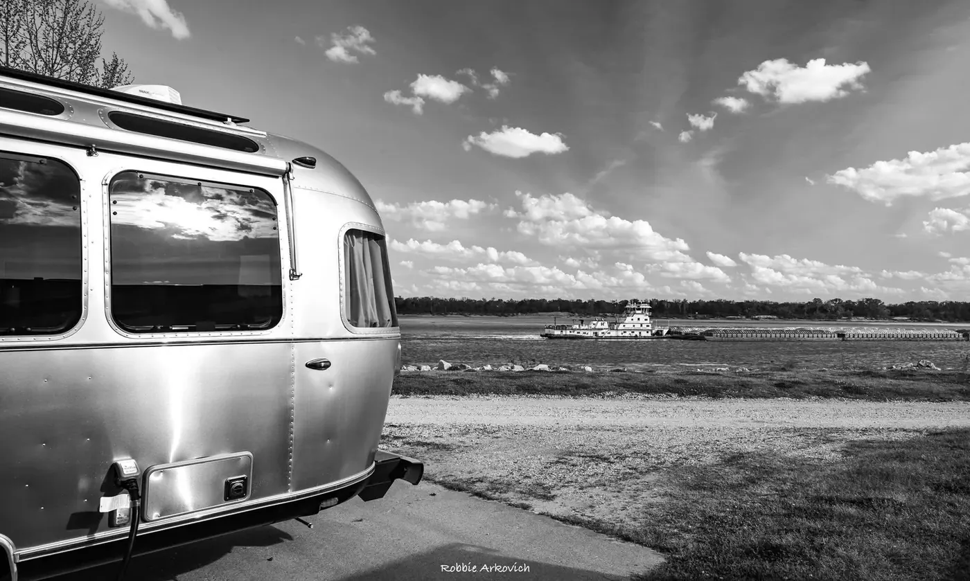 Black and white photo of a polished Airstream under dramatic clouds