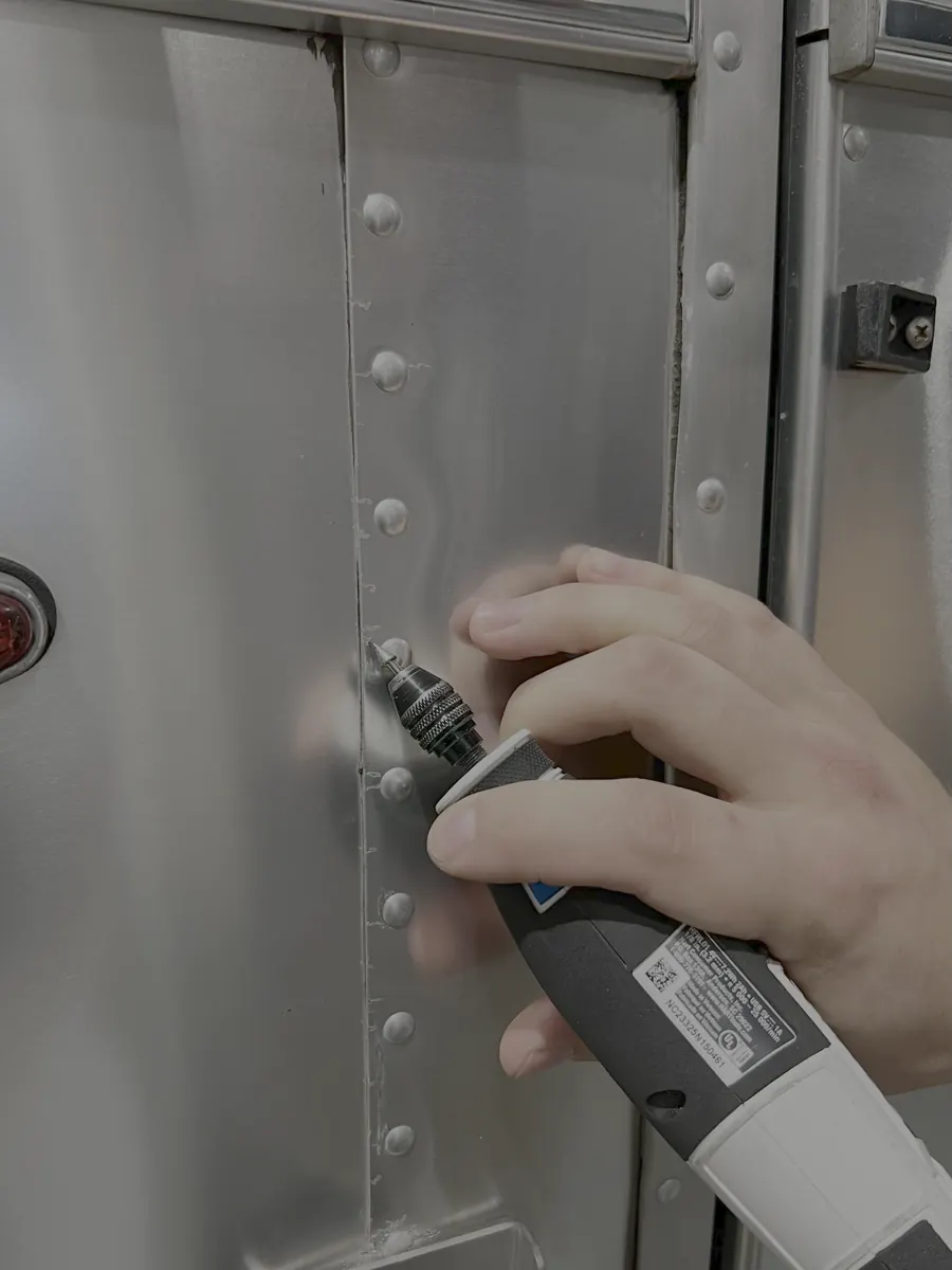 Close-up of a technician drilling out rivets on an Airstream panel