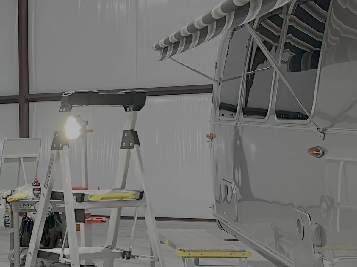 An Airstream inside a repair bay with work lights